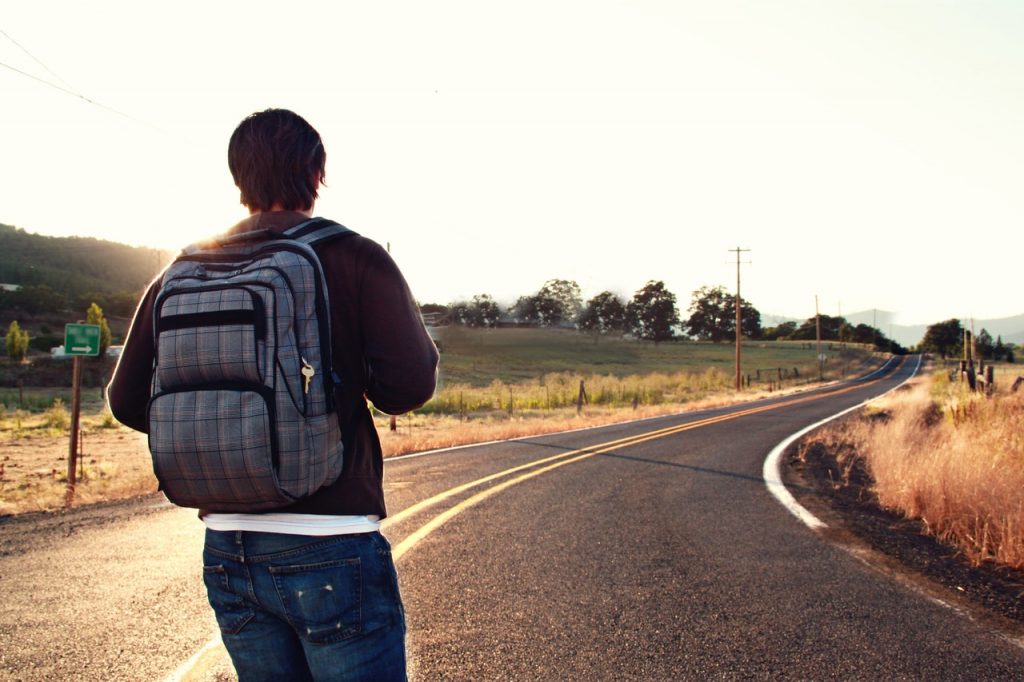 man looking out on road with backpack