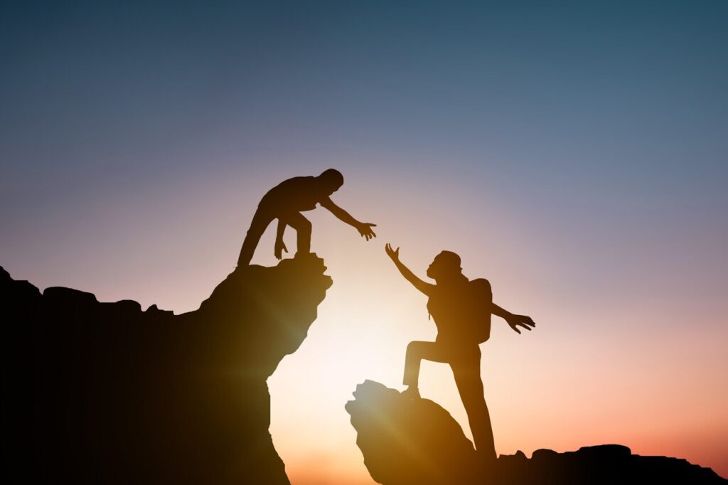 man reaching out for support on a bolder - outdoor therapy