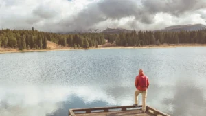 Comprehensive Alcohol Rehabilitation Program in Boulder - man standing at a lake surrounded by mountains