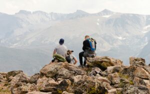 Three men sitting together on a rocky outcrop high in the Colorado Rockies, looking out across the mountains.
