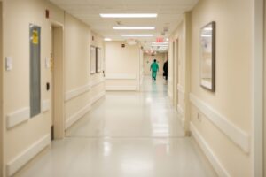 A quiet hospital corridor with a clinician walking away in the distance.